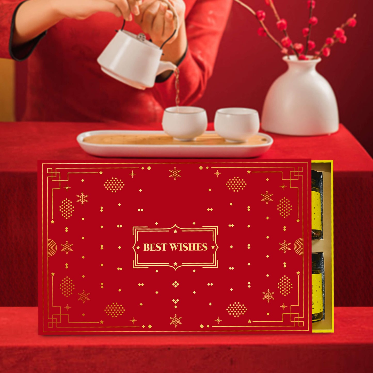 Tea ceremony setup with a red gift box labeled 'Best Wishes' on a red tablecloth.