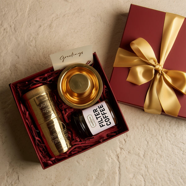 Gift set with gold tumbler, coffee packaging, and card on a textured surface