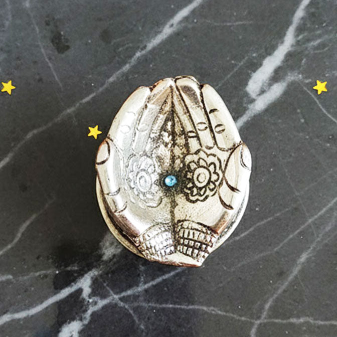 German Silver Hand-Shaped Diya with floral engravings placed on marble with marigolds