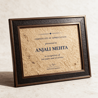 A4 certificate of appreciation printed on natural jute fibre in a bronze and black textured frame, standing against a pale wall