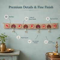 Full length of the jute lotus toran on a plain wall with its parts labelled — jute base, lotus and rosette motifs, pearl tassels and the finish