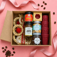 Diwali hamper packed in its kappa board box with the gold zari jute toran, kahwa and coffee jars, two cookie jars, a boxed ceramic diya and four stacked rice husk kulhads