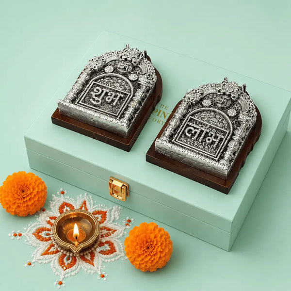 Shubh and Labh plaques seen from above on the closed gift box, showing the embossed metal face wrapping an arch-shaped dark wooden base