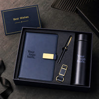 Navy corporate gift set with gold accents — notebook, pen, keychain and flask arranged in a premium navy presentation box
