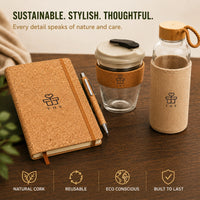 Sustainable cork gift set on desk — cork notebook with pen, double-wall glass coffee cup with cork sleeve and borosilicate bottle with jute sleeve