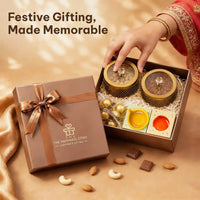 A hand in festive dress lifting a dry fruit jar lid from an open Diwali gift hamper, with the words Festive Gifting Made Memorable