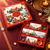 Angled view of the open Favourites of India gift box, showing four regional snack boxes in a cross layout and four painted clay diyas in corner wells