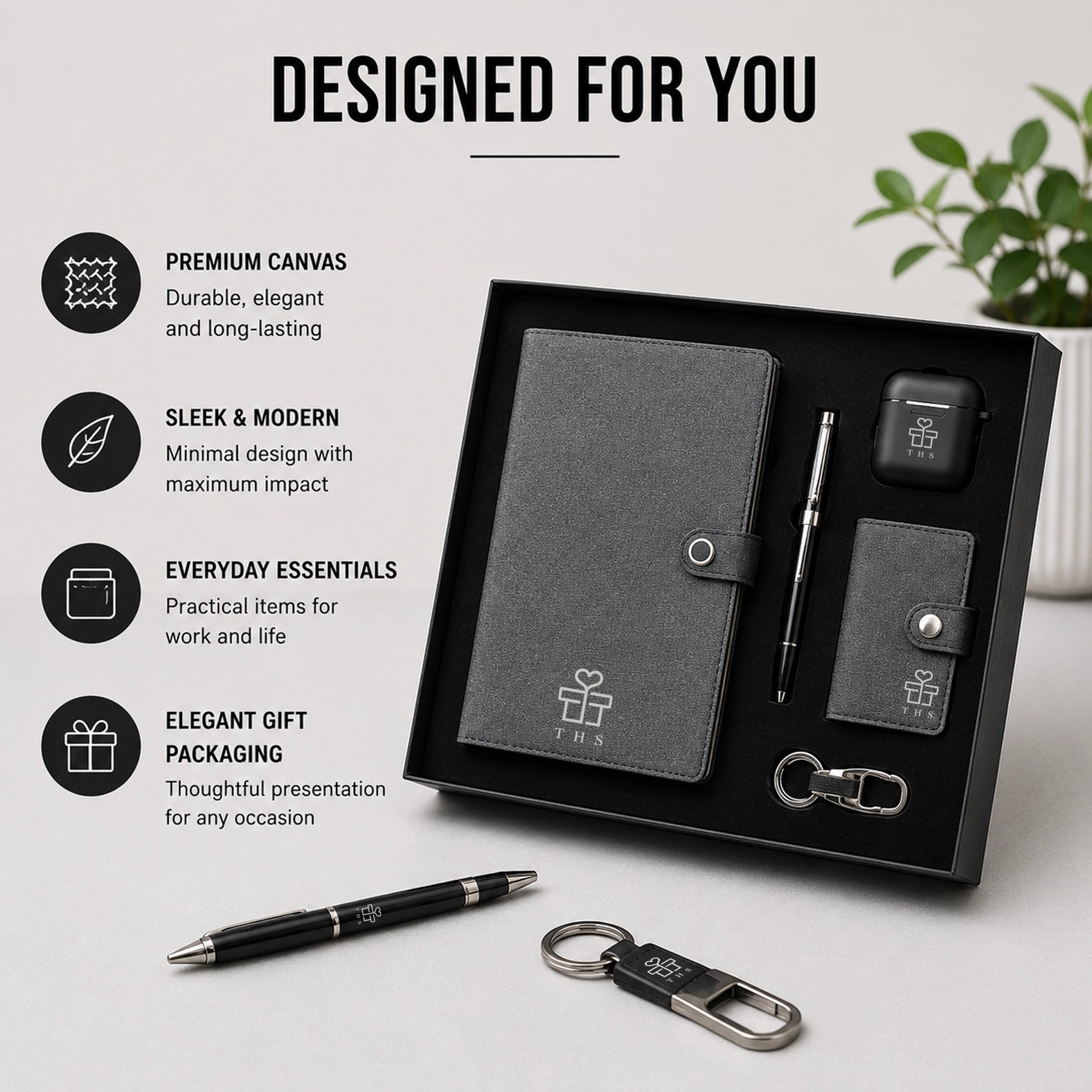 Canvas Core executive gift set styled on desk — grey canvas notebook, pen, earbuds case, snap-tab card holder and keychain with black packaging