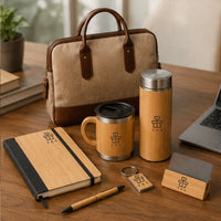 Premium bamboo corporate gift set styled on a desk with laptop bag, vacuum bottle, insulated mug, notebook, pen and card holder — sustainable client gifting set with logo