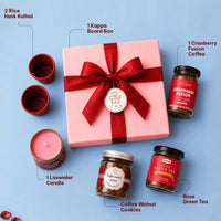 Labelled contents of the tea and coffee gift hamper — kappa board box with a red ribbon and wish tag, two rice husk kullads, a lavender candle, cranberry fusion instant coffee, coffee walnut cookies and rose green tea