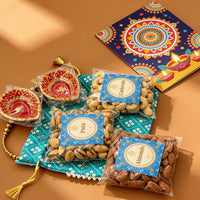 Angled view of the Diwali potli hamper with sealed packs of cashews, pistachios and almonds, wrapped hand-painted diyas and a mandala-printed Diwali card