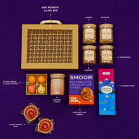 Labelled contents of the premium Diwali gift box — MDF carry case, jars of cashews, pistachios, almonds and chocolates, scented candle, modak and ladoo candles, chocolate chip cookies, incense sticks and two hand-painted diyas