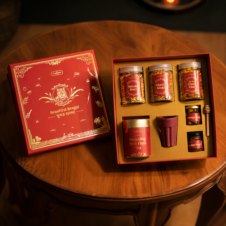 The Beautiful Bengal Box — foil-stamped red lid with the Royal Bengal Tiger emblem, surrounded by Masala Muri, Khasta Nimki, Darjeeling First Flush Tea, Sunderban Wild Honey, Mango Pickle and clay cup