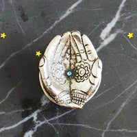 German Silver Hand-Shaped Diya with floral engravings placed on marble with marigolds
