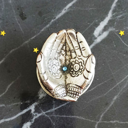 German Silver Hand-Shaped Diya with floral engravings placed on marble with marigolds