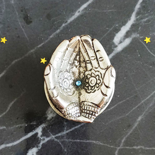 German Silver Hand-Shaped Diya with floral engravings placed on marble with marigolds