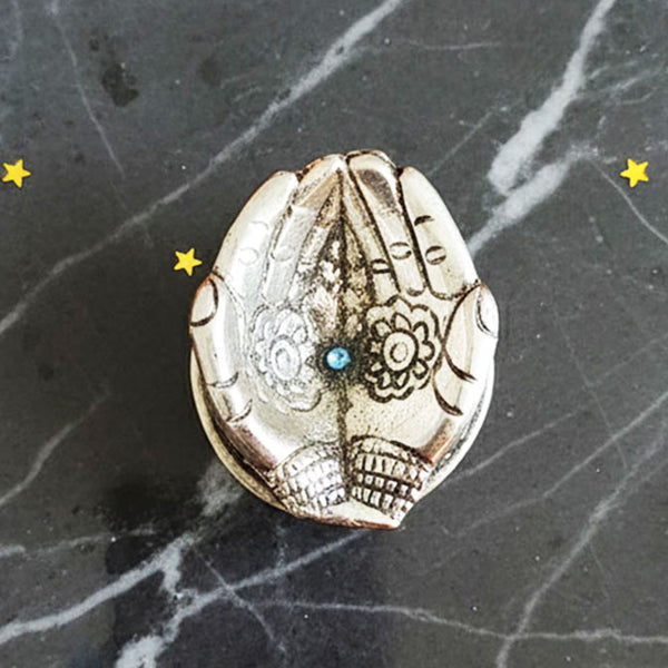 German Silver Hand-Shaped Diya with floral engravings placed on marble with marigolds