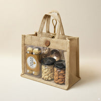 Eco Treasure Hamper with reusable jute bag containing Ferrero Rocher chocolates, cashews in jar, almonds in jar, and decorative golden urli diya.