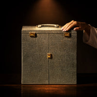 Hand resting on the closed Royal Majesty tea set trunk against a dark background — luxury gift beyond ordinary