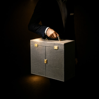 Man in a suit holding the closed Royal Majesty tea set trunk by its handle — premium tea set gift