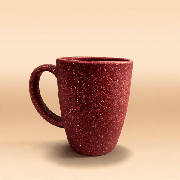 Wine crimson rice husk coffee mug with a closed loop handle, shown three-quarter on a warm neutral surface