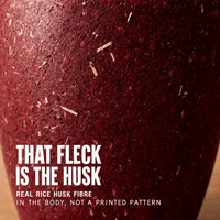 Close view of the rice husk composite wall, pale husk fibres suspended in the crimson body