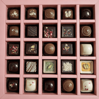 Overhead view of 25 different decorated chocolates in a pink divided gift box tray
