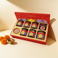 Subh Deepavali gift hamper open in the red elephant box: Maharaja Masala Chai, Kashmiri Kahwa Chai, Signature Bold Coffee, chocolates, Diwali nut mix, mouth freshener, ghee and a scented candle, with a brass diya and marigolds