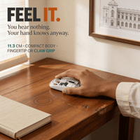 Hand resting on the compact 11.3 cm transparent wireless mouse on a wooden desk, showing its real size and fingertip grip
